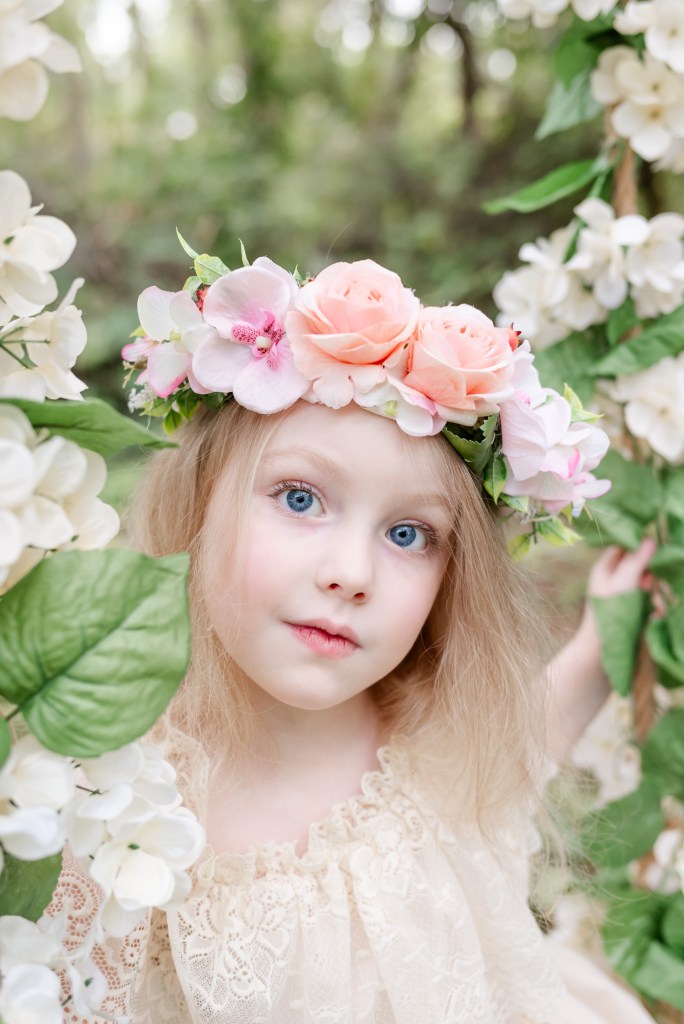 A young girl. Sitting on a floral swing. Portrait photo. Late summer no