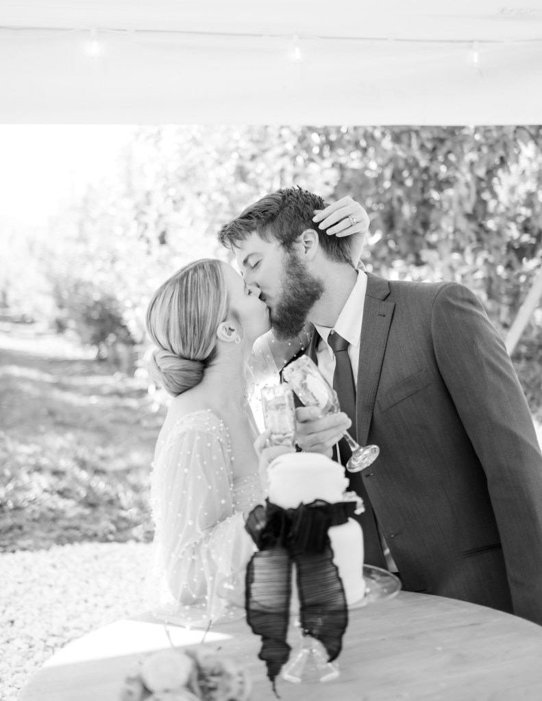 A wedding couple kissing while cutting their wedding cake taken by Shannon Eileen Photography